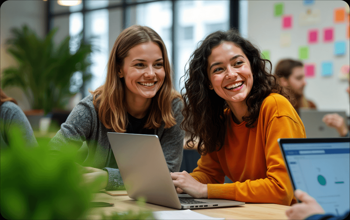 Two colleagues smiling while working on a laptop